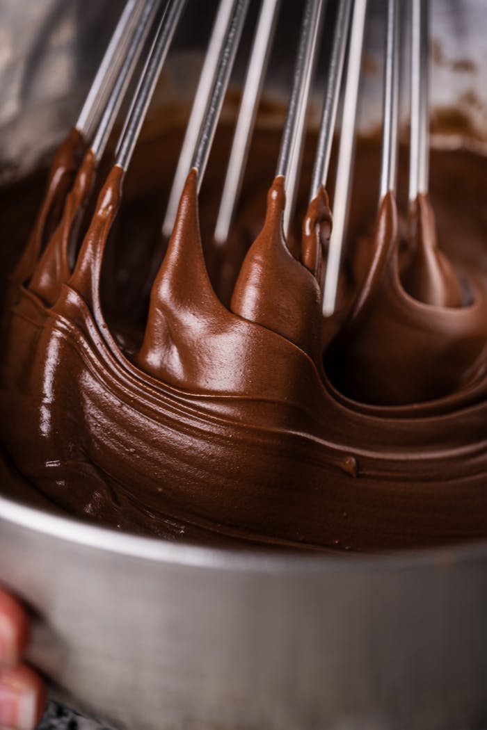 Close-up of thick, creamy chocolate batter being whisked in a metal bowl.